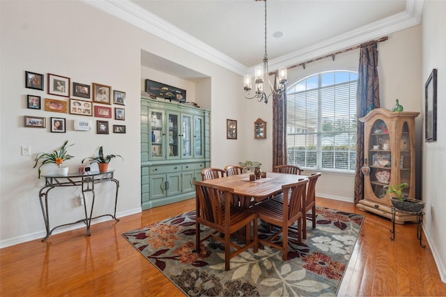 dining space featuring crown molding, wood-type flooring, and an inviting chandelier