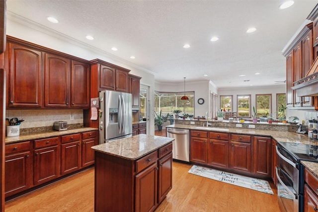 kitchen with light stone counters, a center island, light wood-type flooring, appliances with stainless steel finishes, and kitchen peninsula