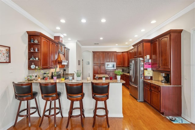 kitchen featuring appliances with stainless steel finishes, a breakfast bar, backsplash, kitchen peninsula, and light hardwood / wood-style flooring