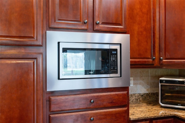 interior space with stainless steel microwave, backsplash, and light stone counters