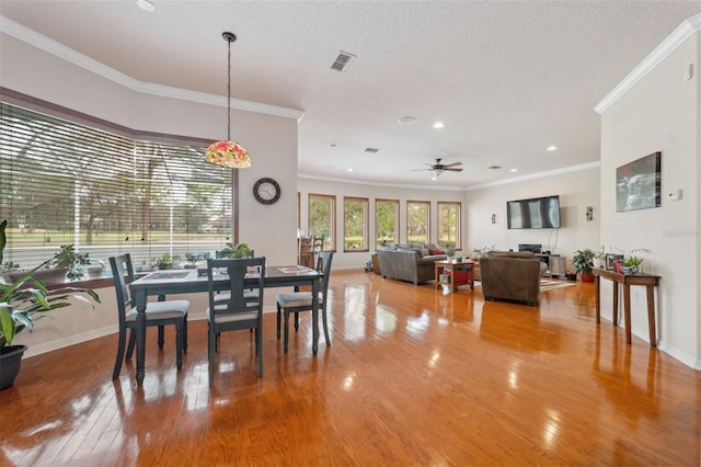 dining space with hardwood / wood-style floors, a textured ceiling, ornamental molding, and ceiling fan