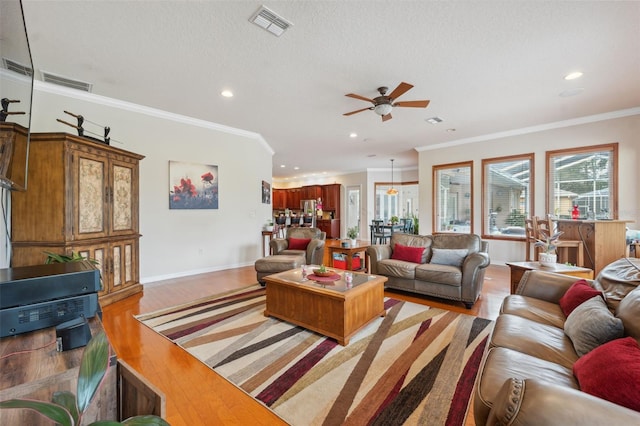 living room with ceiling fan, crown molding, light hardwood / wood-style flooring, and a textured ceiling