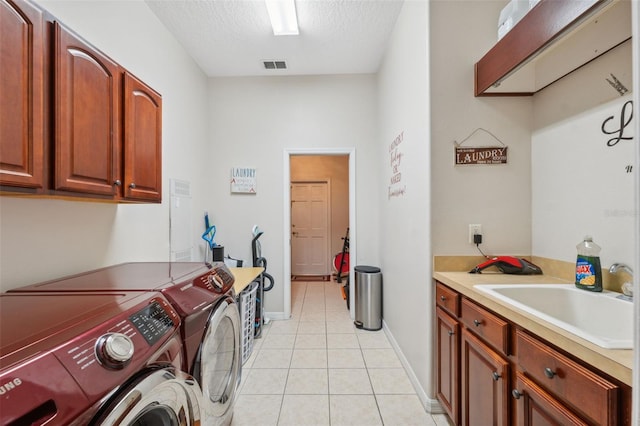 laundry area featuring light tile patterned flooring, sink, cabinets, separate washer and dryer, and a textured ceiling