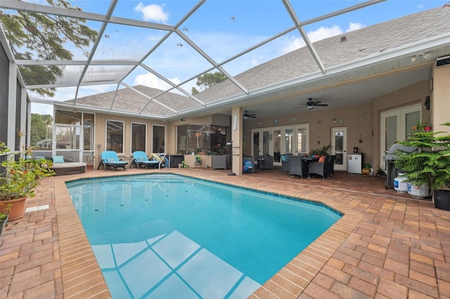 view of pool with a patio area, ceiling fan, and glass enclosure