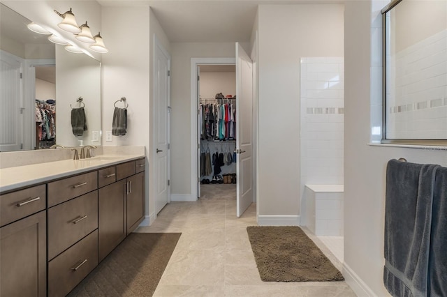 bathroom featuring a walk in shower, baseboards, a walk in closet, and vanity