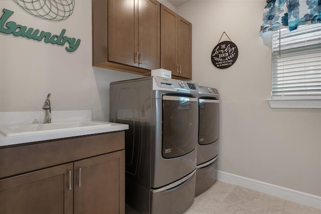 washroom featuring cabinet space, baseboards, separate washer and dryer, a sink, and light tile patterned flooring