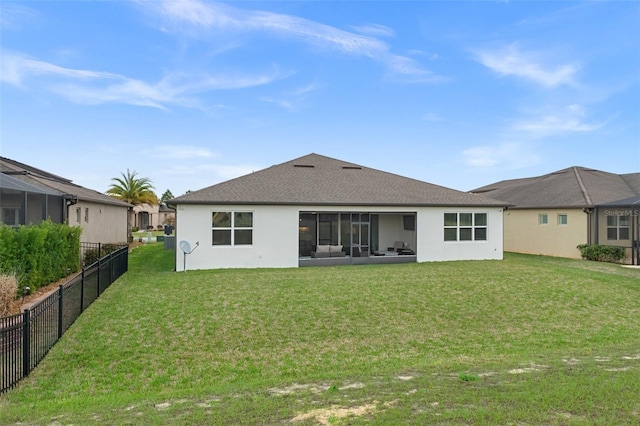 rear view of property featuring a yard, fence, and stucco siding