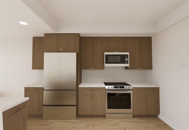 kitchen featuring white microwave, light countertops, stainless steel gas range, light wood-type flooring, and freestanding refrigerator