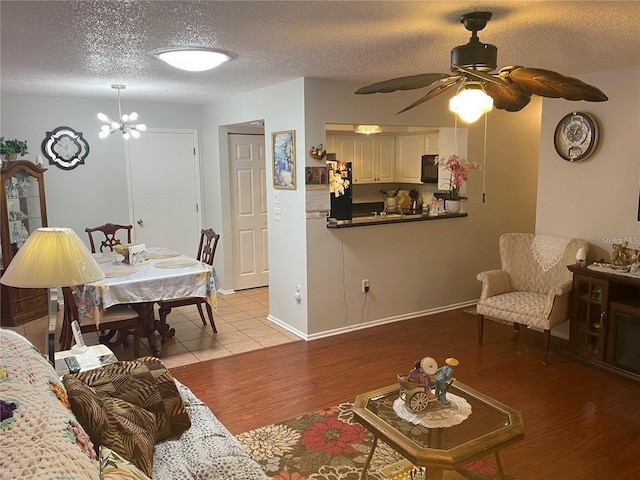 living room with a chandelier, a textured ceiling, and light wood-type flooring