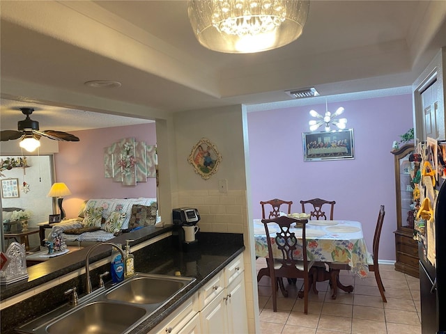 kitchen featuring sink, white cabinetry, light tile patterned floors, a raised ceiling, and ceiling fan with notable chandelier