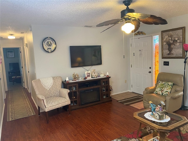 living room with ceiling fan, dark wood-type flooring, and a textured ceiling