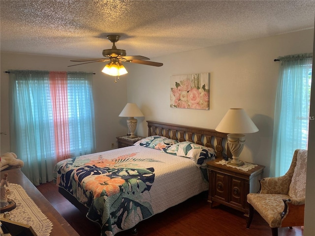 bedroom with ceiling fan, dark hardwood / wood-style flooring, multiple windows, and a textured ceiling