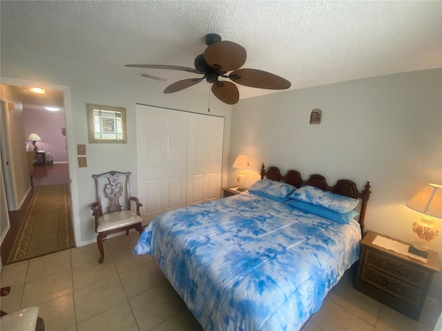 bedroom with ceiling fan, a textured ceiling, a closet, and light tile patterned floors