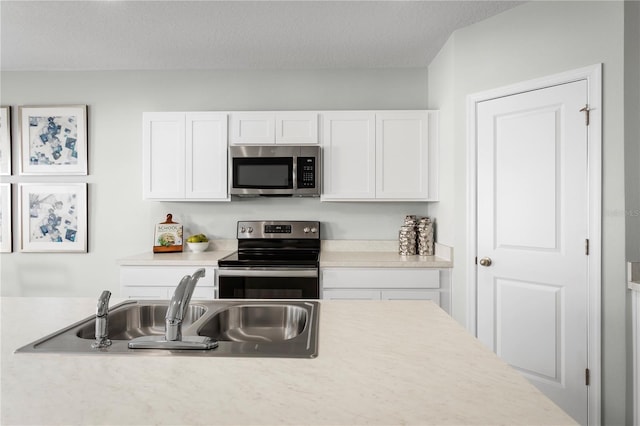 kitchen featuring sink, stainless steel appliances, white cabinetry, and a textured ceiling