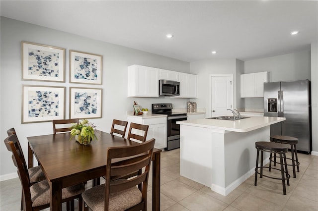 kitchen featuring a center island with sink, a kitchen breakfast bar, stainless steel appliances, sink, and white cabinetry