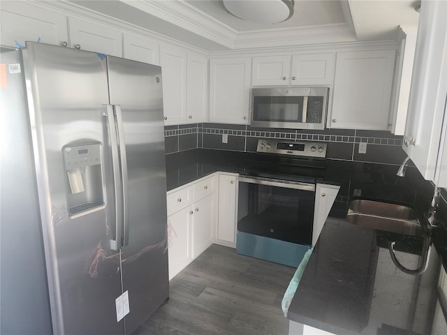 kitchen featuring white cabinetry, appliances with stainless steel finishes, dark hardwood / wood-style floors, and backsplash