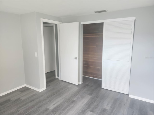 unfurnished bedroom with a closet and dark hardwood / wood-style floors