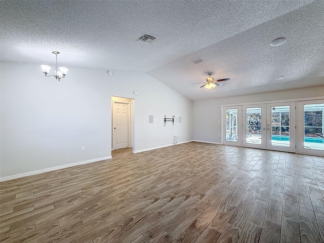 unfurnished living room featuring ceiling fan with notable chandelier, visible vents, vaulted ceiling, and wood finished floors