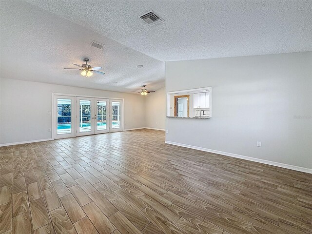 unfurnished living room with visible vents, vaulted ceiling, wood finished floors, and french doors