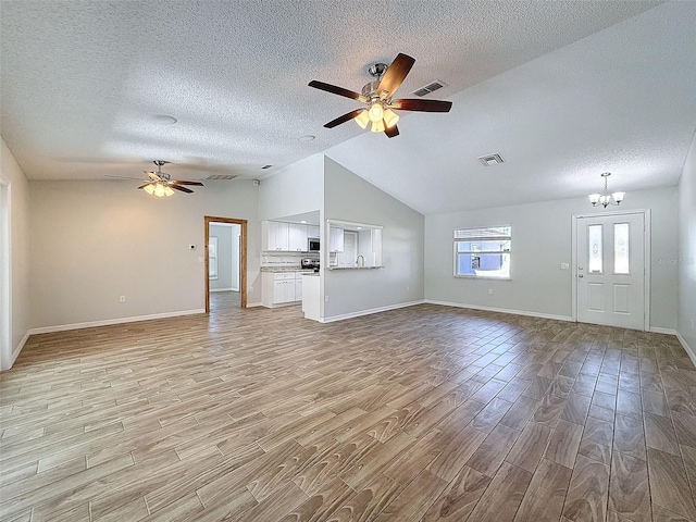 unfurnished living room featuring visible vents, vaulted ceiling, light wood-style flooring, and ceiling fan with notable chandelier