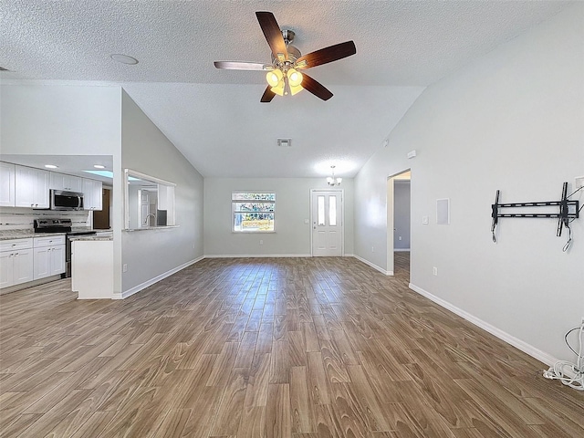 unfurnished living room featuring baseboards, a textured ceiling, visible vents, and wood finished floors