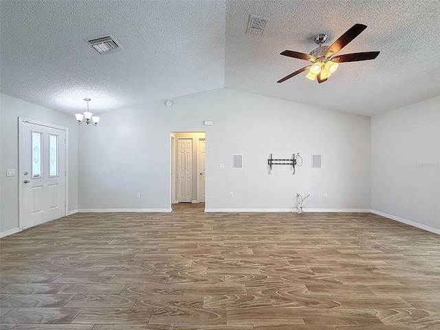 unfurnished room featuring ceiling fan with notable chandelier, lofted ceiling, visible vents, and wood finished floors