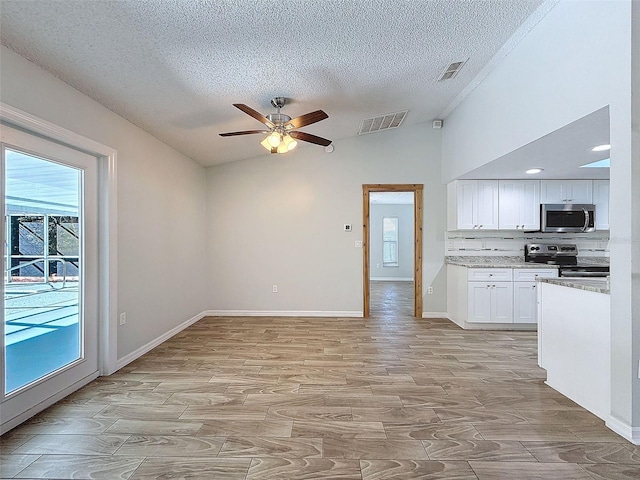 kitchen with lofted ceiling, appliances with stainless steel finishes, visible vents, and white cabinets