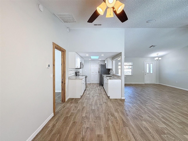 kitchen with light countertops, open floor plan, visible vents, and light wood-style flooring