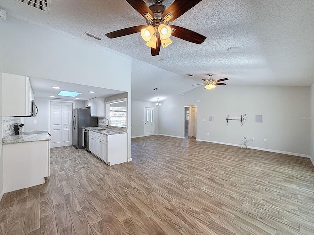 kitchen featuring open floor plan, visible vents, a sink, and light wood finished floors