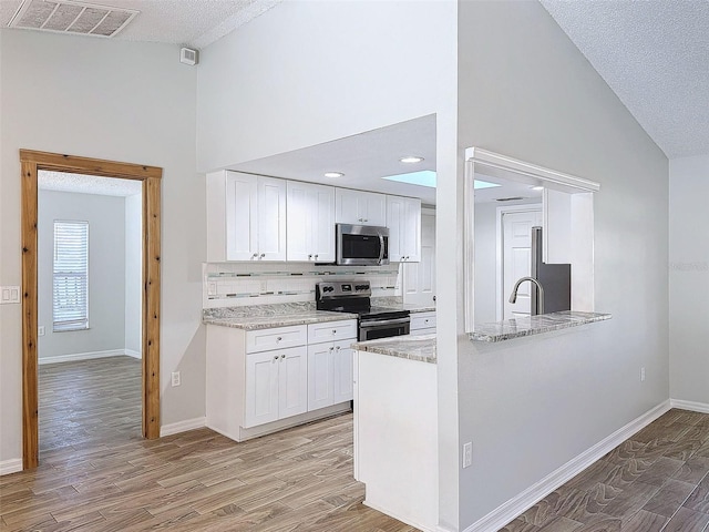 kitchen with tasteful backsplash, visible vents, appliances with stainless steel finishes, white cabinets, and light wood-type flooring