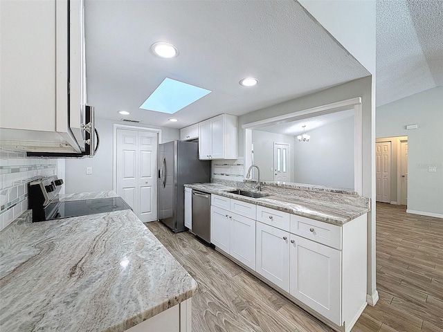 kitchen featuring appliances with stainless steel finishes, light wood-type flooring, a sink, and white cabinets