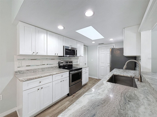 kitchen featuring stainless steel appliances, light stone counters, a sink, and decorative backsplash