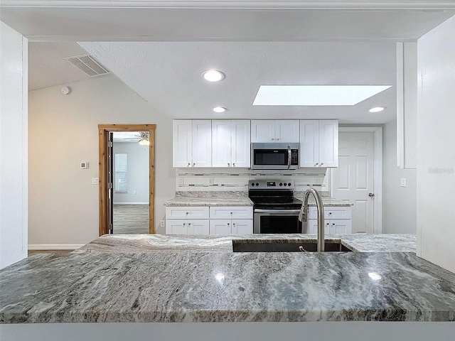 kitchen featuring stone countertops, visible vents, white cabinets, appliances with stainless steel finishes, and tasteful backsplash