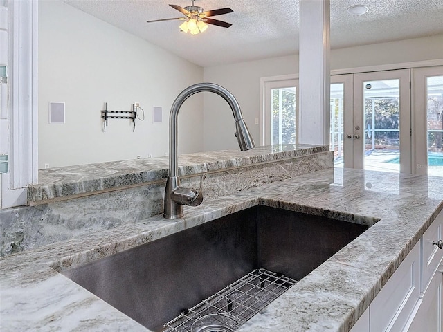 room details featuring a textured ceiling, a sink, white cabinetry, and a ceiling fan