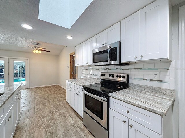 kitchen featuring stainless steel appliances, light wood-style flooring, white cabinets, and decorative backsplash