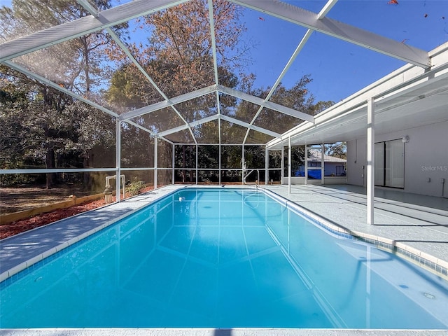 pool featuring glass enclosure and a patio area