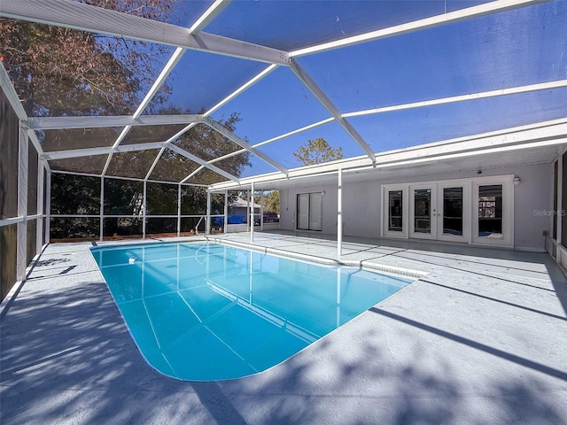 outdoor pool with a lanai, a patio area, and french doors