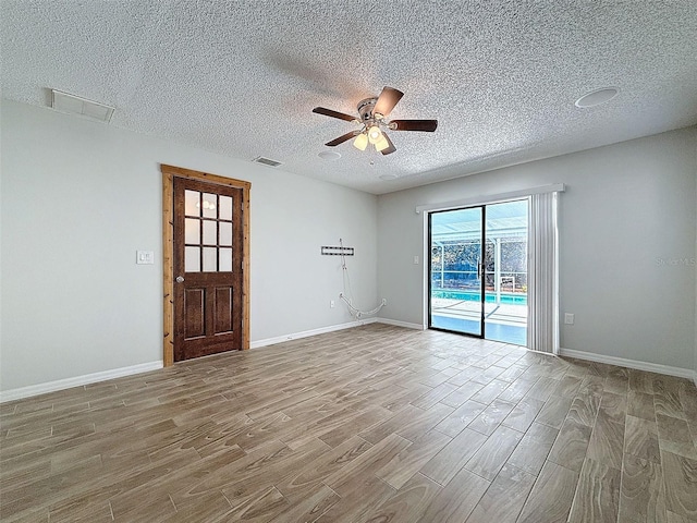 empty room with visible vents, ceiling fan, baseboards, and wood finished floors