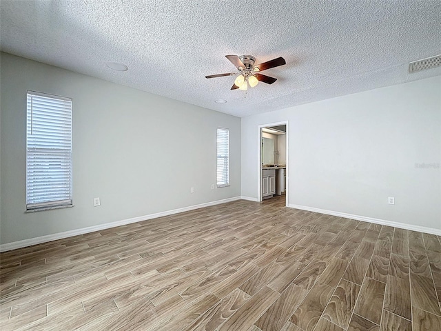 spare room with baseboards, visible vents, ceiling fan, wood finished floors, and a textured ceiling