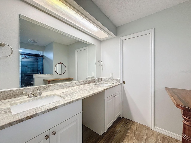 full bathroom featuring double vanity, visible vents, a sink, and wood finished floors