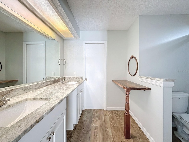 bathroom with a textured ceiling, wood finished floors, a sink, and toilet