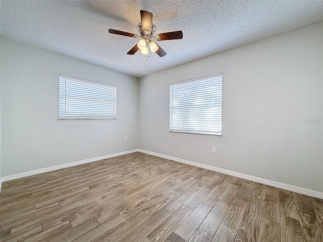 spare room featuring a textured ceiling, baseboards, and wood finished floors