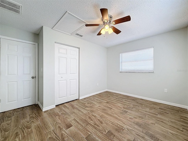 unfurnished bedroom with a closet, visible vents, a textured ceiling, and wood finished floors