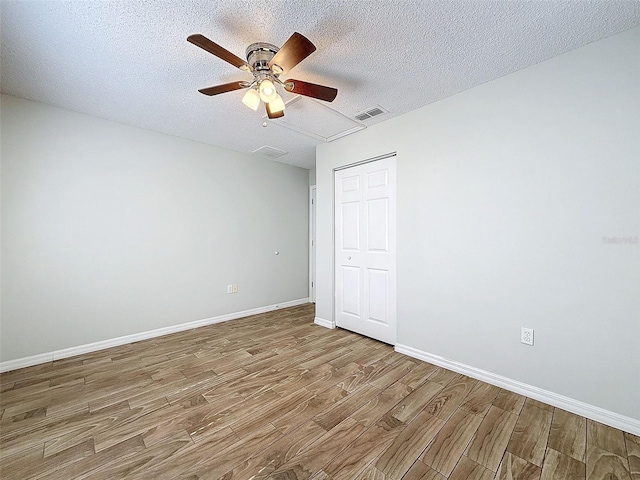 unfurnished room featuring visible vents, a ceiling fan, a textured ceiling, wood finished floors, and baseboards