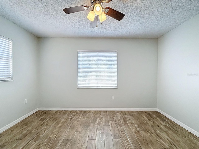 spare room with a ceiling fan, a textured ceiling, baseboards, and wood finished floors