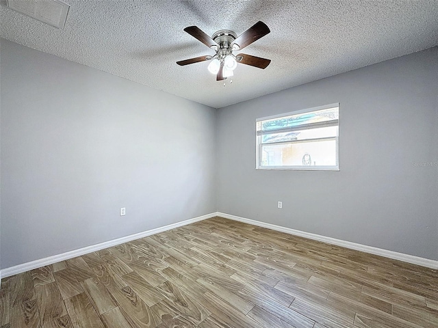 unfurnished room featuring a textured ceiling, wood finished floors, visible vents, and baseboards