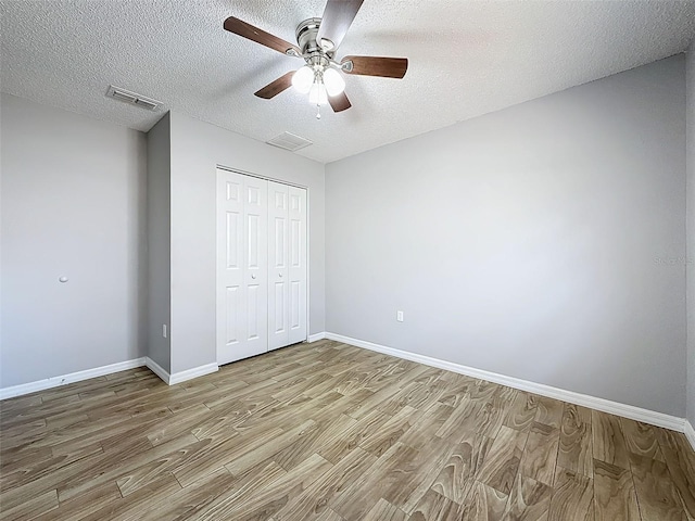 unfurnished bedroom featuring baseboards, a closet, visible vents, and wood finished floors