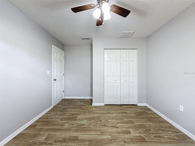 unfurnished bedroom with baseboards, visible vents, wood finished floors, a textured ceiling, and a closet