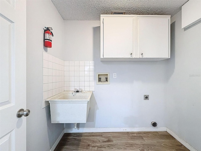 laundry area with washer hookup, cabinet space, hookup for an electric dryer, a textured ceiling, and wood finished floors