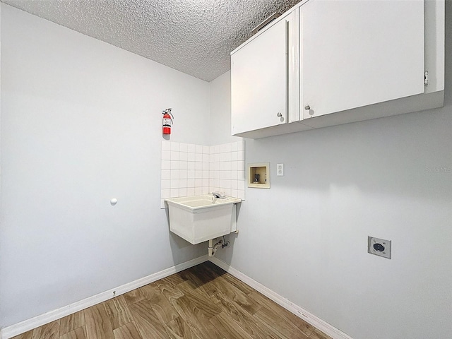 laundry area with cabinet space, wood finished floors, hookup for an electric dryer, washer hookup, and a sink